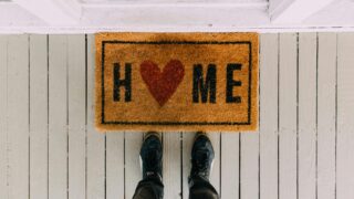 A creative doormat with heart motif symbolizing home at a front porch entrance.